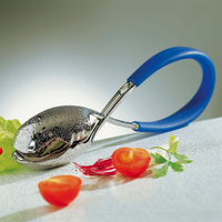 The Casa Bugatti KISS Salad Tong, with its shiny metal finish and blue handle, rests on a light surface beside cherry tomatoes, red chili pepper pieces, parsley, and lettuce—a stylish accessory for summer entertaining.