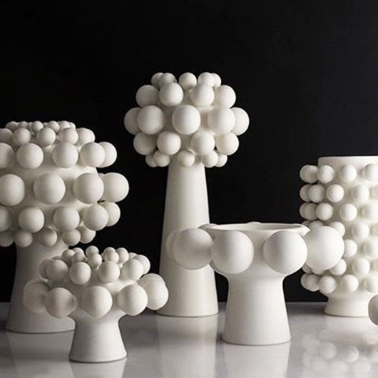 Five Nimbus Dome Vase Onyx pieces by KleinReid—unique handmade porcelain vases with raised spheres—are arranged on a glossy surface against a dark background.