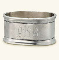 The MATCH Oval Napkin Ring Set of Two by MATCH features elegant monogram-style engraving and double-line borders, offering a timeless pewter look inspired by classic handmade designs.