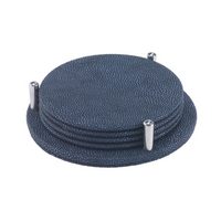 The Bodrum Stingray Coaster Set of 4 features round, textured dark blue coasters with a subtle metallic finish, neatly stacked on a matching holder with three silver metal pegs.