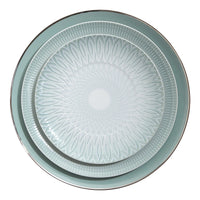Two round plates from the Vista Alegre Venezia Dinnerware collection nest together: the smaller plate features a geometric design, while the larger showcases a solid rim with a metallic edge, all in light blue-green porcelain.