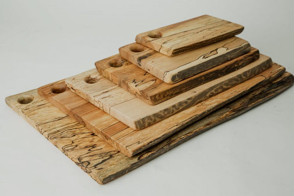 The Peterman Spalted Maple Live Edge Board 21" features unique grain patterns and a round hole in one corner, showcased on a white background.