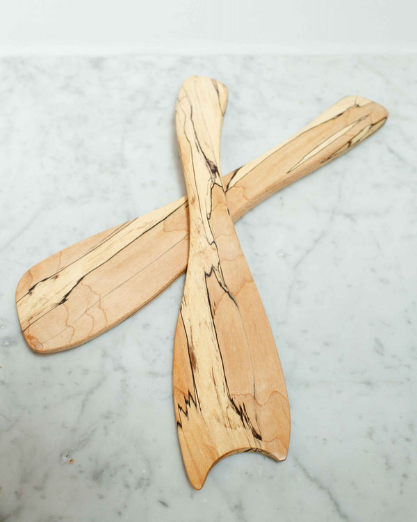 Two Spalted Maple Rustic Salad Tossers by Peterman, featuring dark grain patterns, are crossed on a white marble surface.